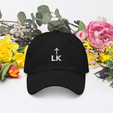 corner cap jnjdjdnbjnddbnksckn featuring black hat with LK embroidery against floral background.